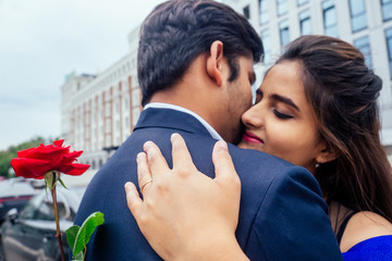 Wall Mural - long haired brunette indian woman in blue dress with her handsome boyfriend having dating .man giving rose to his girlfriend in summer downtown street.I said yes