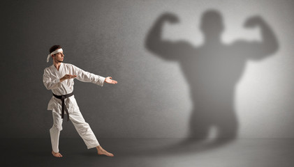 Wall Mural - Young karate man fighting with a big black scary shadow