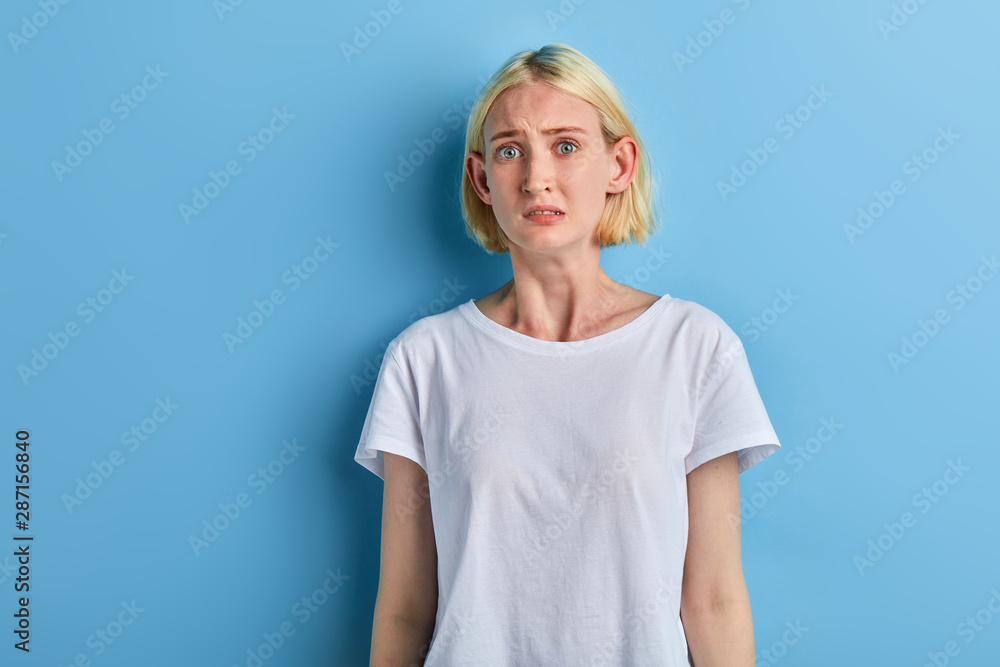 puzzzled worried woman in white T-shirt doesn't know what to do ...