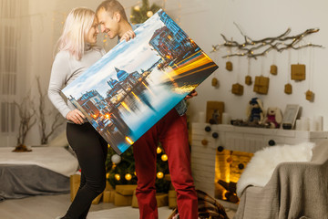 Happy young woman and her boyfriend holding canvas while moving into new home