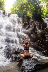 Poster - Woman practices yoga near waterfall in Bali, Indonesia