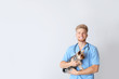 Veterinarian with cute dog on light background