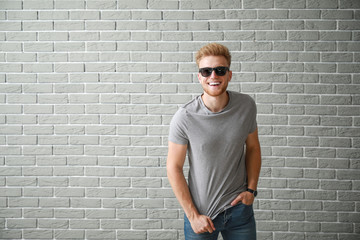 Canvas Print - Man in stylish t-shirt near brick wall