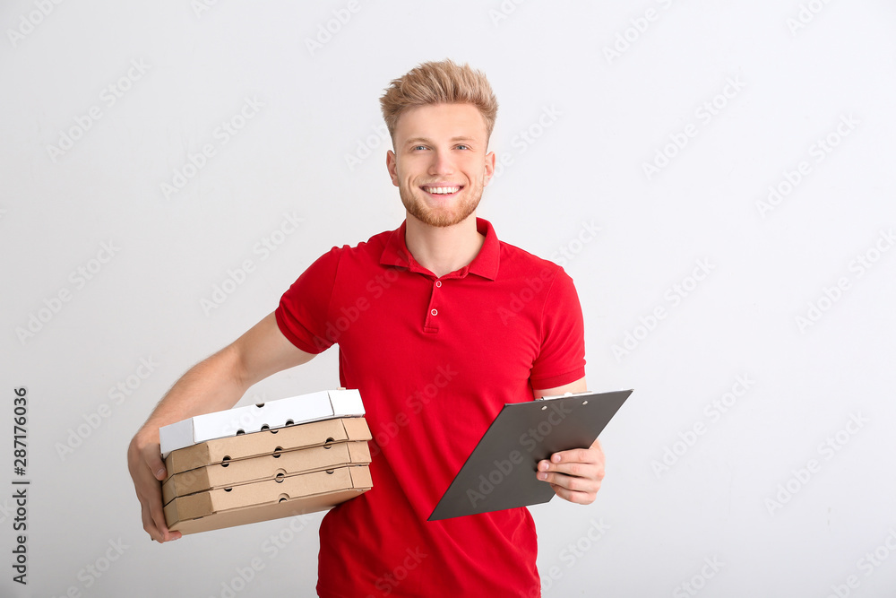 Handsome worker of food delivery service on light background