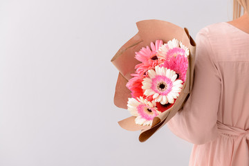 Wall Mural - Woman with bouquet of beautiful gerbera flowers on light background