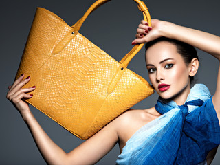 Stylish beautiful  woman wearing blue scarf  with yellow handbag