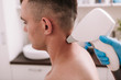 Cropped shot of a man getting laser hair removal treatment at beauty clinic. Beautician removing excessive hair on the back of the neck of a male client