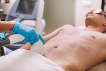 Beautician Removing Pubic Hair Of A Male Client With Laser. Man Getting Laser Hair Removal Treatment