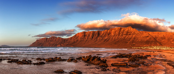 Wall Mural - Panorama of Caleta de Famara beach, famous surfing resort on Lanzarote, Canary islands, Spain.