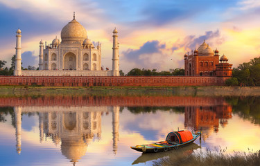 Fototapete - Taj Mahal Agra at sunset on the banks of river Yamuna with moody sunset sky and view of wooden boat used for tourist ride on the river 