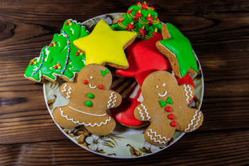 Wall Mural - Plate with tasty festive Christmas gingerbread cookies on wooden table. Top view