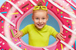 © wayhome.studio  - Close up portrait of cheerful adorable ginger girl sticks head through pink rubber ring, wears goggles and bright t shirt, spends summer holiday at seaside, enjoys swimming. Happy childhood and rest