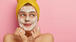 Cropped image of lovely young woman washes face with foaming soap, has pleased facial expression, keeps hands together under chin, has morning routine, stands against pink studio wall with blank space