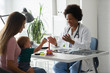 © lordn - Female doctor pediatrician with baby patient and mother. Pediatrician doing an infant medical exam. Early child development and care