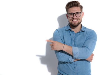 Poster - smiling young casual man pointing finger to side