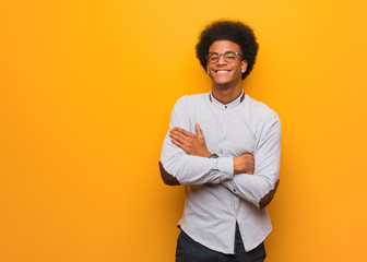 Wall Mural - Young african american man over an orange wall crossing arms, smiling and relaxed