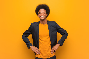 Wall Mural - Young business african american man over an orange wall with hands on hips