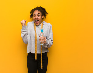 Young fitness black woman surprised and shocked.Holding a water bottle.