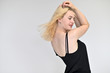 © Вячеслав Чичаев - Portrait of a cute blonde student girl, a young woman in a black dress with beautiful curly hair on a white background in different poses. Shows hands to the sides. Beauty, brightness, emotions.