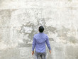 © khosrork - Backside of young man in checkered blue shirt and sunglasses standing against concrete gray wall. looking at background empty copyspace.