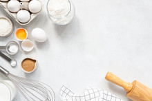 Cooking And Baking Ingredients Utensils On White Concrete Background. Kitchen Food Frame. Eggs Sugar Milk Whisker Rolling Pin And Measuring Spoons With Spices