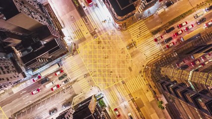 Wall Mural - 4K UHD Hyperlapse time-lapse of car traffic and people crossing road at night in Hong Kong city downtown. Drone aerial top view, fly upward. Commuter, Asia city life or public transportation concept