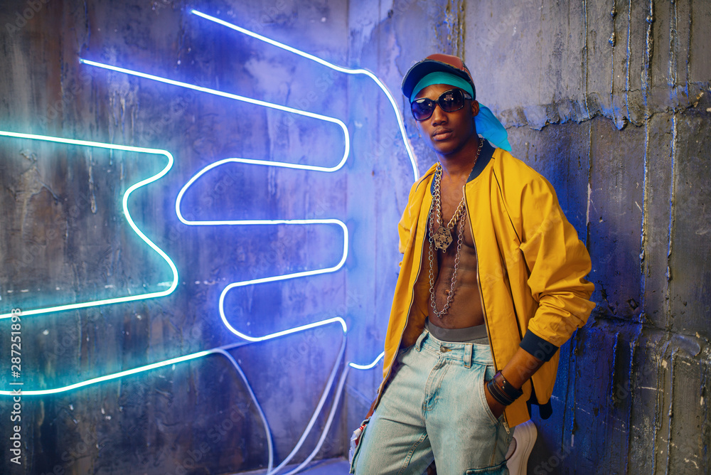 Black rapper in underpass neon light on background - obrazy, fototapety, plakaty 