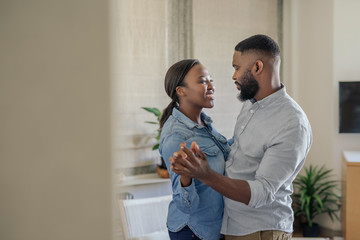 Poster - Smiling young African American couple dancing together at home