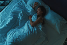 Young Beautiful Girl Or Woman Sleeping Alone In Big Bed At Night, Top View, Blue Toned