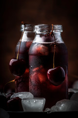 Canvas Print - Cherry juice, cold beverage with ice in glass bottles on vintage wooden table, low key, copy space