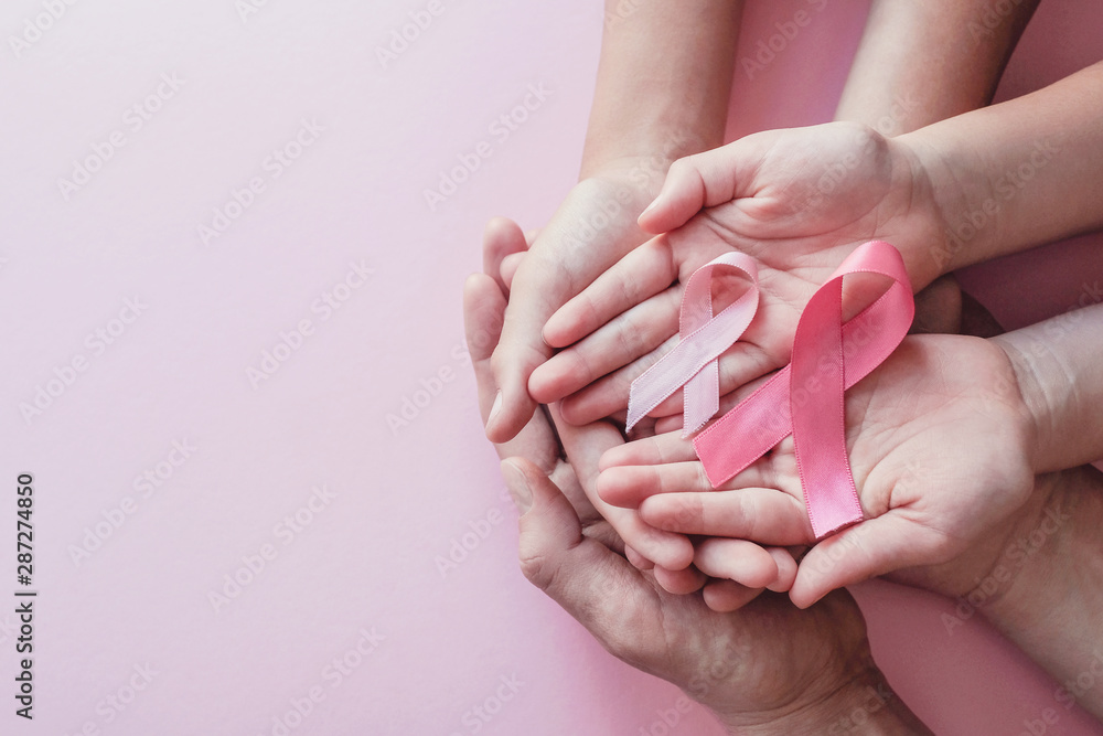 hands holding pink ribbons on pink background, Breast cancer awareness and October Pink day, World cancer day - obrazy, fototapety, plakaty 
