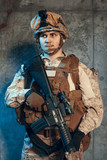 Fototapeta  - fully equipped army soldier in camo uniform and helmet, armed with pistol and assault service rifle