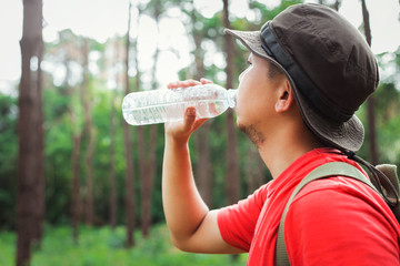 tourists, the young man a break to drink water during the journey in the jungle. The concept of tourism in holidays, The natural background of green trees.