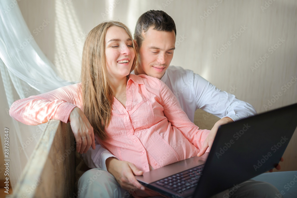 beautiful young couple uses a laptop a puddle on the sofa in the room ...