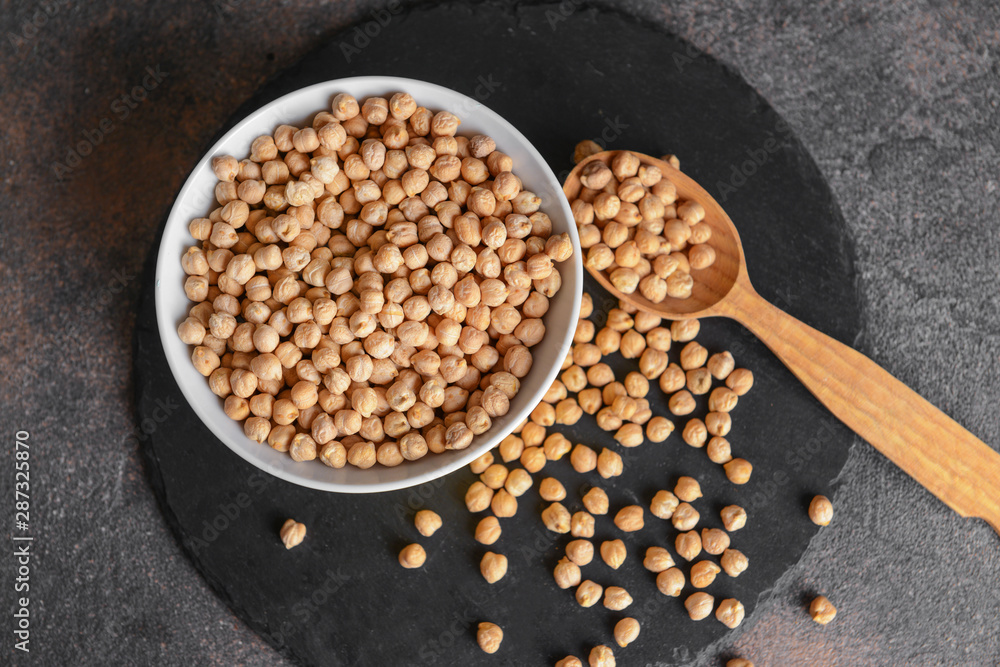 Bowl with raw chickpea and spoon on table
