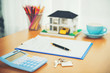 © chingching - House model, calculator and house key lying on real estate contract, home loan and investment concept.