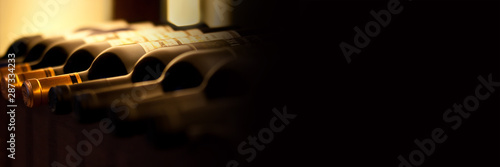 Fotomural Bottles of red wine on a wooden shelf, panoramic banner with black background