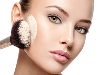 Wall Mural - woman applying dry cosmetic tonal foundation on the face