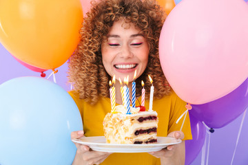 Sticker - Image of delighted young woman celebrating birthday with multicolored air balloons and piece of cake