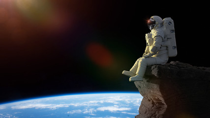 Poster - astronaut sitting on a cliff on the Moon in front of planet Earth