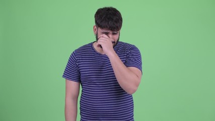 Wall Mural - Stressed young overweight bearded Indian man looking sad and crying