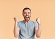 © GVS - Happy man celebrating his success with winner gesture on beige background