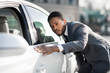© Prostock-studio - The final check. Afro man examining new car at dealership