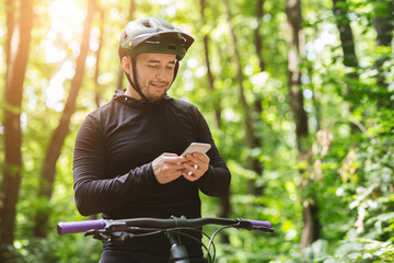 Smiling cyclist holding smartphone, checking on new messages