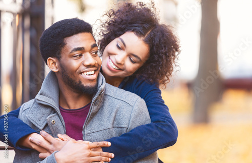 Cuadros en Lienzo Cute black girl flirting with boyfriend, hugging from behind