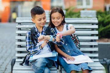 A little boy child in a blue T-shirt  shows the girl his smart watch and presses a finger.