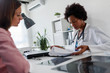 © lordn - Doctor talking with patient at desk in medical office. Health care concept, medical insurance. Womens health.