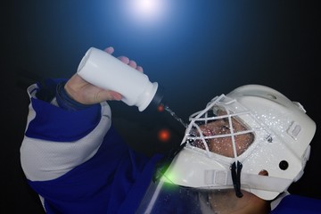 Wall Mural - Hockey goalie drinks water.Detail of a male face in a white goalie hockey mask.This is a detail hockey goalie. He is  drinking.