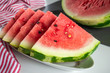 Triangular slices of ripe watermelon with red flesh served on white plate
