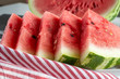 Close up of triangular slices of ripe watermelon with red flesh served with striped napkin
